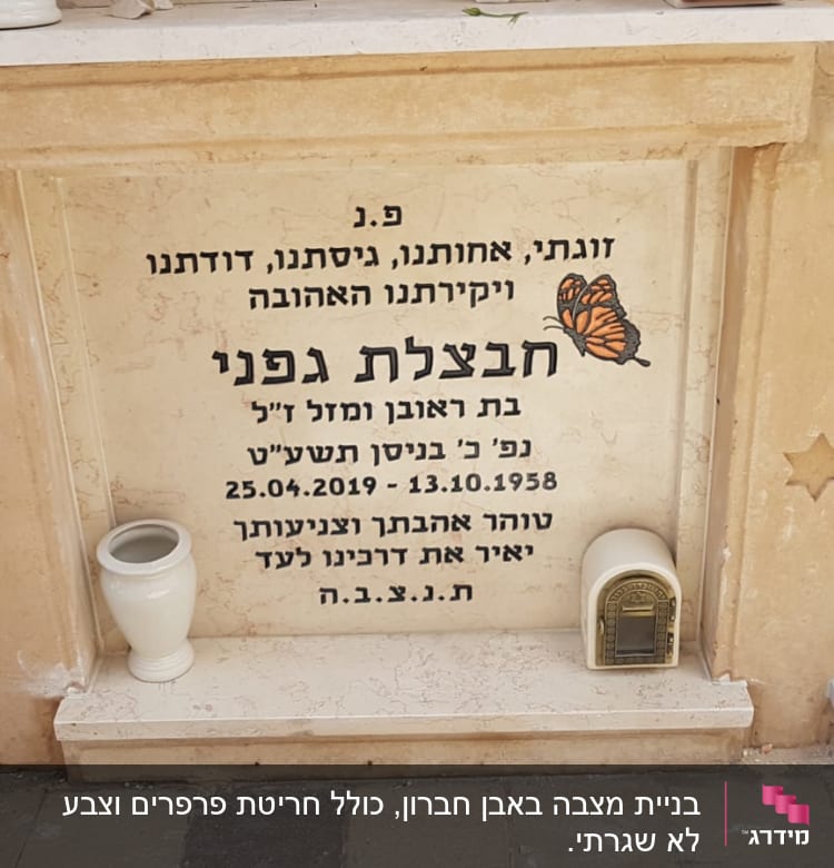 מצבה עם כיתוב בעברית ופרפר, אגרטל ונר זיכרון